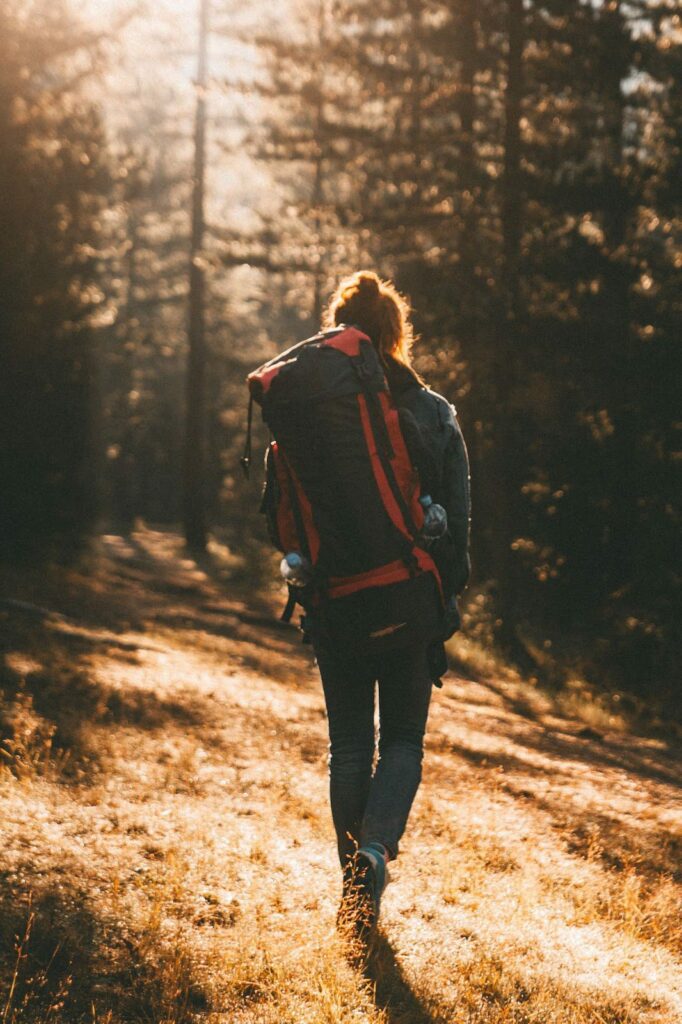 A woman hiking in the woods with a backpack.